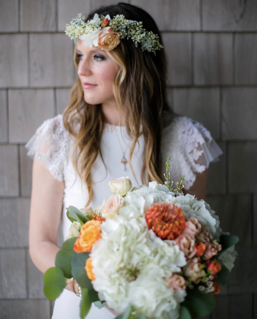 beautiful blooms by obx wedding flowers this big bridal bouquet features large white flowers with accents of orange and yellow flowers, bride is wearing a flower crown with white flowers and orange and yellow accents, outer banks wedding, obx wedding flowers
