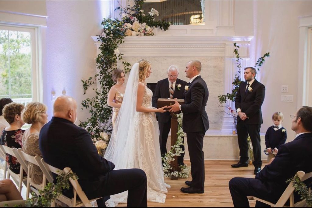 bride and groom at the alter on their wedding day inside of venue in outer banks north carolina - flowers designed and arranged by obx wedding flowers