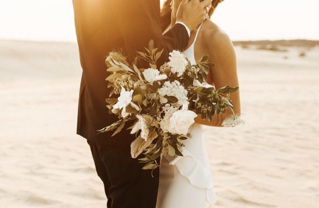couple in embrace after wedding on outer banks beach in north carolina - OBX wedding Flowers