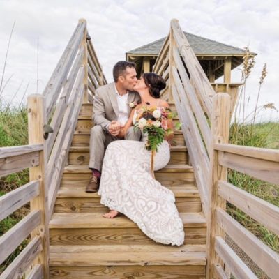couple kissing on outer banks walkout to beach wedding floral arrangements and design by obx wedding flowers