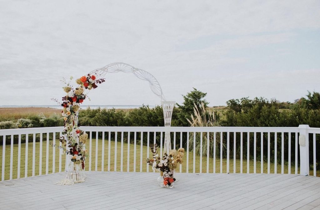 white arch arbor with floral design by obx wedding flowers beach wedding outer banks