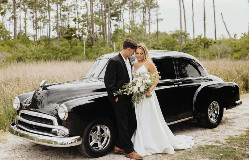 couple with classic car beautiful floral arrangement obx wedding flowers