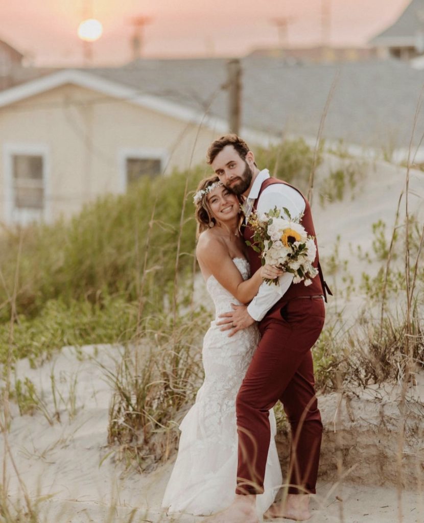 couple in embrace at beach wedding outer banks north carolina obx wedding flowers floral design