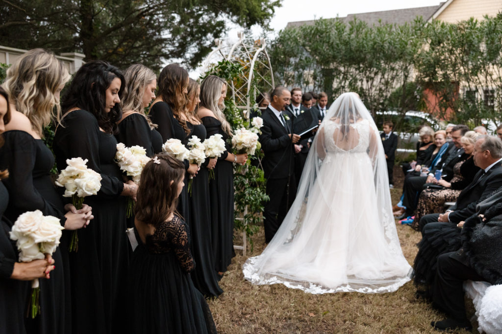 bride in white wedding dress standing at the alter with her groom, white wedding flowers on the aisle runner of beautiful outer banks wedding, obx wedding flowers, outer banks wedding flowers