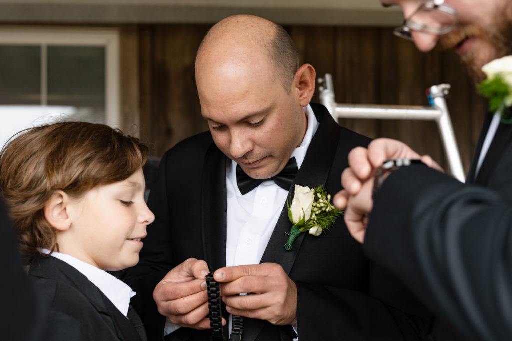 Groom and boy getting ready for outer banks wedding, white boutonnieres on black tuxedos are an elegant and timeless wedding look, obx wedding flowers 